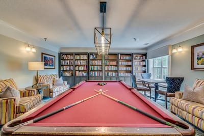 A cozy billiards room with bookshelves and seating