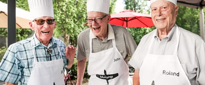 Three residents in chef hats smiling outdoors