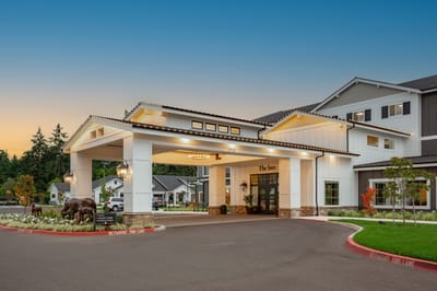 Welcoming entrance of The Inn at University Village with outdoor lighting and landscaping.