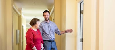 Staff member assisting a resident in a hallway