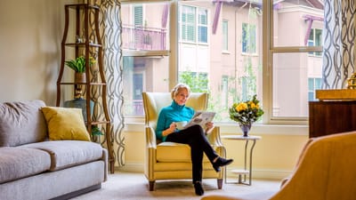 A resident reading a newspaper in a cozy chair