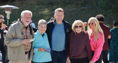 Residents and staff smiling together outdoors at a social event