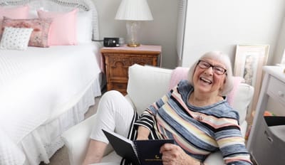 Resident joyfully reading in a cozy room