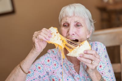 A woman enjoying a cheesy meal in a dining setting