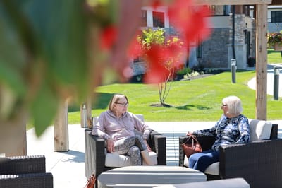 Two residents chatting in a landscaped outdoor area