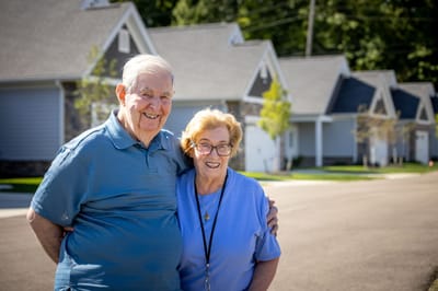 Senior couple smiling in front of residential buildings