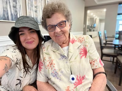 A resident and staff member smiling together in the facility's common area