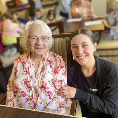 A resident and staff member smiling together in an activity room