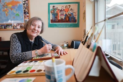 A resident painting at a table with art supplies
