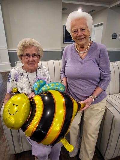 Two residents celebrating with a balloon in a common area
