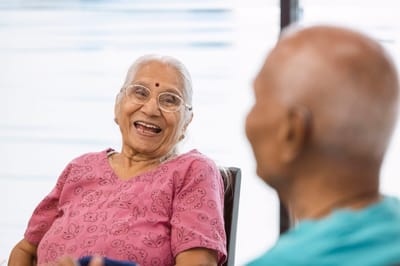 Two seniors smiling and chatting in a common area