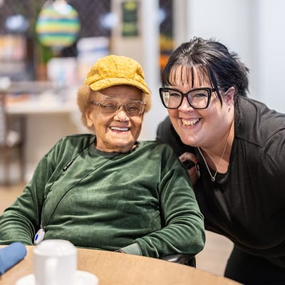 A resident and staff member smiling together in an activity area