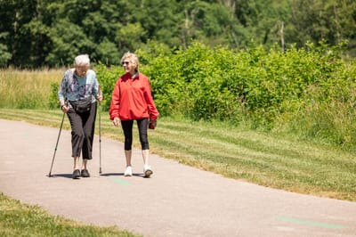 Two women walking on a paved path in a garden