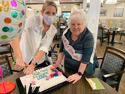 Staff and resident celebrating with a birthday cake