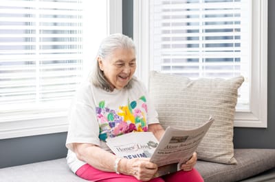 Senior resident reading a newspaper in a bright room