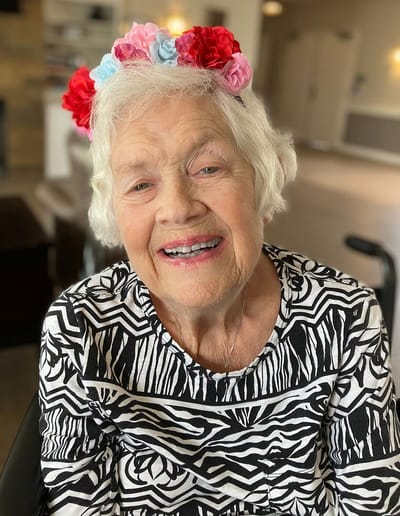 Smiling resident wearing a flower crown in activity area
