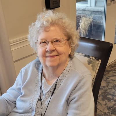 A smiling elderly woman in a cozy setting