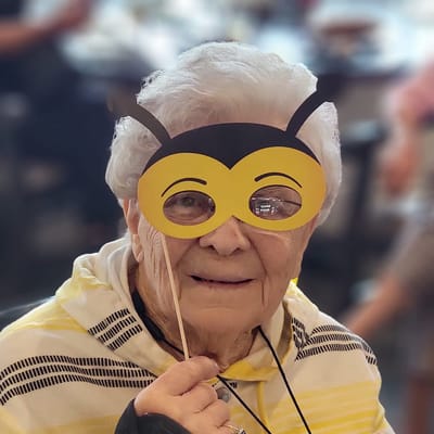 Resident wearing a playful bee mask during an activity