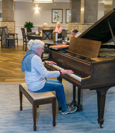 Resident playing piano in a common area