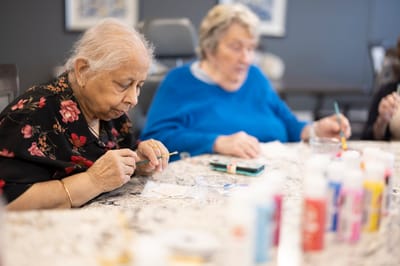 Residents engaged in a painting activity at a crafting table