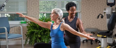 An instructor assisting a senior lady in a fitness class