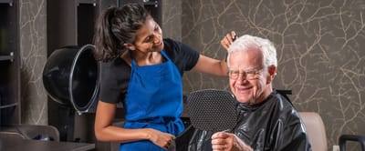 A staff member styling a resident's hair in the salon