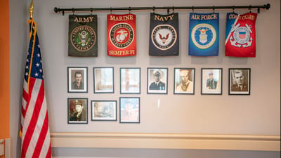 Wall display honoring military veterans with flags and photos