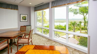 A bright interior room with large windows showing outdoor views