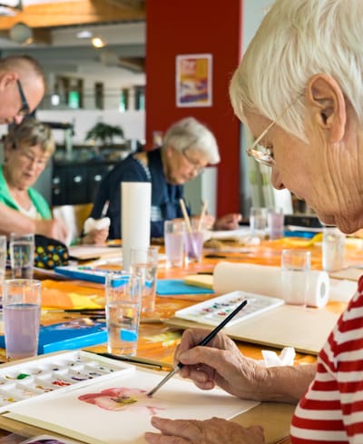 Residents participating in a painting activity in an indoor space