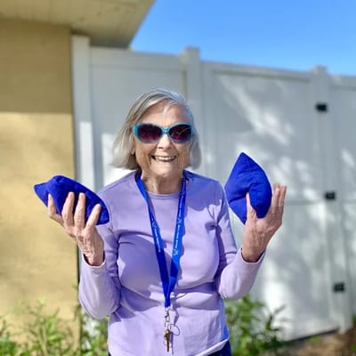 Senior resident outdoors, smiling and holding blue objects