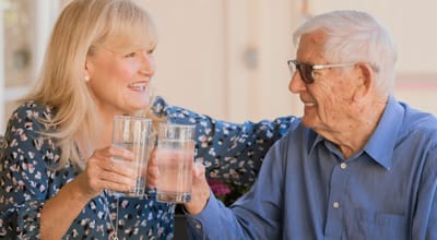 Two residents toasting with glasses of water outdoors