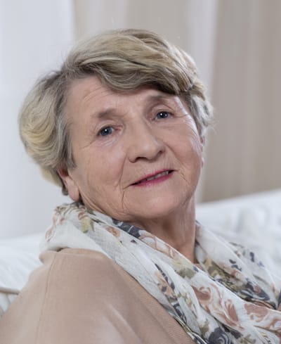 An elderly woman smiling warmly at the camera.