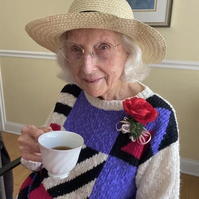Senior resident enjoying tea and wearing a flower corsage