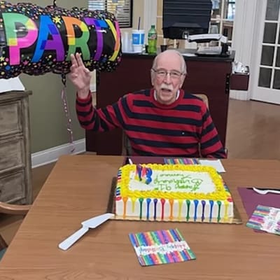 Resident celebrating a birthday with cake and balloon.
