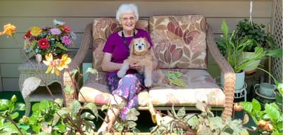 Resident sitting with a dog on a garden bench