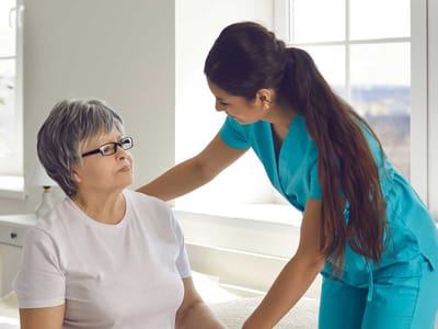 A caregiver assisting an elderly resident in a bright room