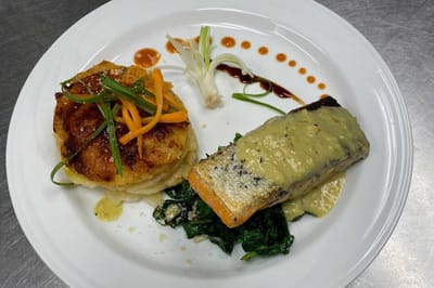 A plate of salmon with side dishes prepared beautifully