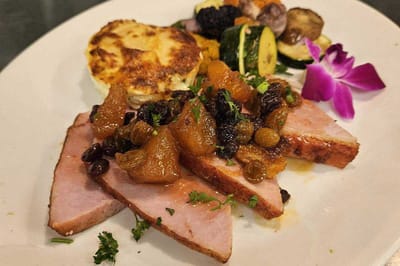 A beautifully plated meal featuring ham and vegetables