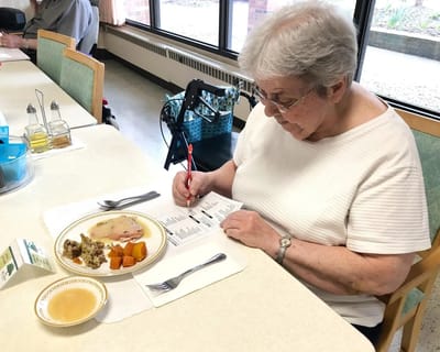 Resident enjoying a meal while filling out a menu