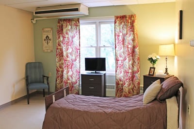 Cozy resident room with floral curtains and a television