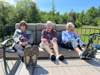 Three seniors relaxing on a patio couch in the sun