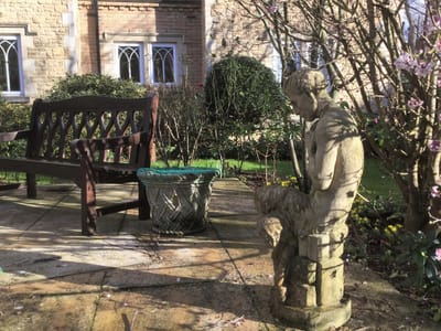Outdoor area with a bench and a statue in a garden
