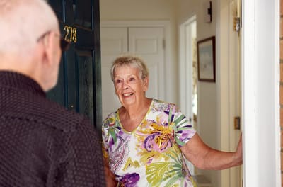 A resident greeting a visitor at the door