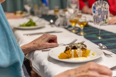 Close-up of a dessert plate with a resident's hand
