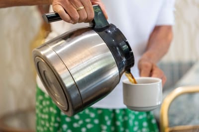 A resident pouring coffee into a cup in a communal area