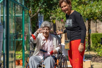 A smiling woman in a wheelchair with staff outside