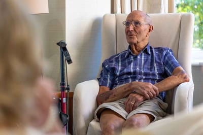 Elderly man sitting in a cozy chair inside a facility