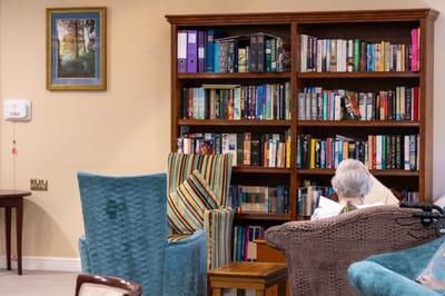 A resident reading a book in a cozy library corner