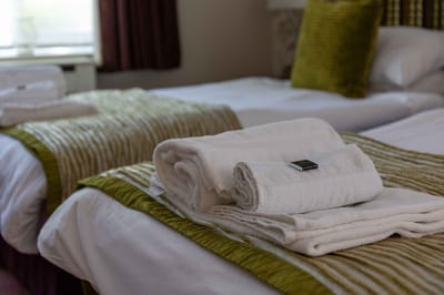 Neatly made beds with towels in a resident room