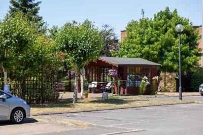 An outdoor garden shed surrounded by trees
